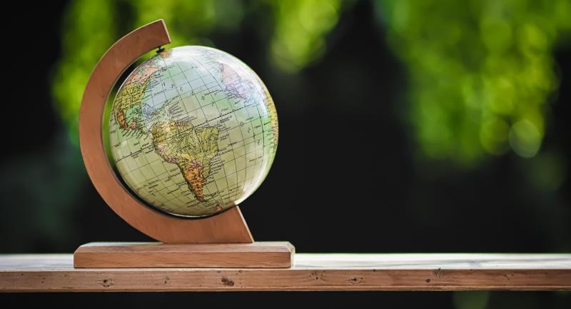 A model globe, showing a map of the world, sits on a wooden bench.